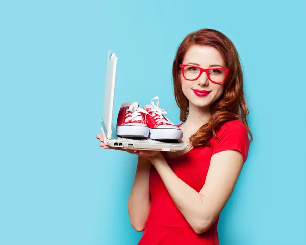 Стильная рыжая девушка с резиновыми туфлями и ноутбуком — стоковое фото