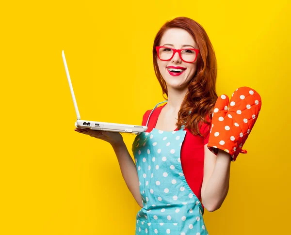 Young housewife with computer and oven gloves — Stock Photo, Image