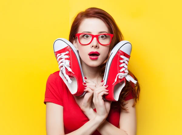 Förvånad rödhårig flicka i röd klänning med joggingskor — Stockfoto