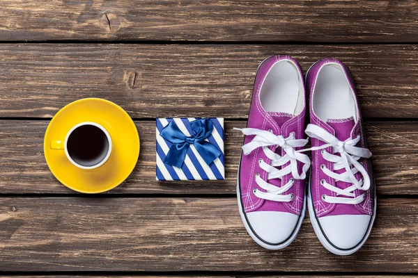 Gumshoes and gift box with coffee cup — Stock Photo, Image