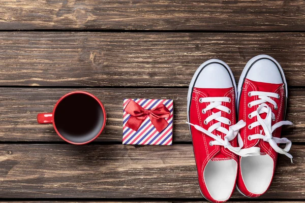 Gumshoes and cup of coffee with gift — Stock Photo, Image