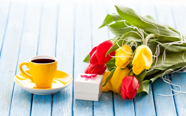 Copo e caixa de presente com buquê de tulipas — Fotografia de Stock