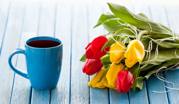 Cup of coffee and bouquet of tulips — Stock Photo, Image