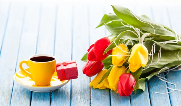 Copo e caixa de presente com buquê de tulipas — Fotografia de Stock