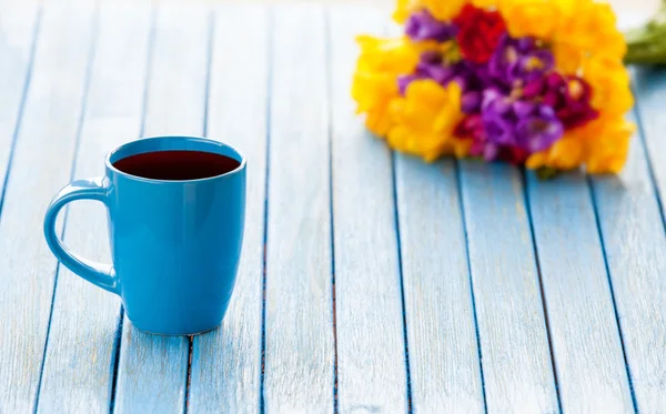 Cup of coffee and bouquet of flowers — Stock Photo, Image