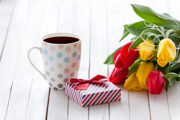 Copo e caixa de presente com buquê de tulipas — Fotografia de Stock