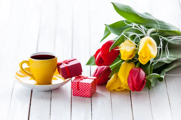 Cup en geschenk doos met boeket van tulpen — Stockfoto