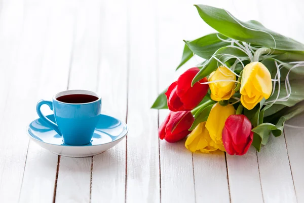 Xícara de café e buquê de tulipas — Fotografia de Stock