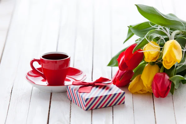 Copo e caixa de presente com buquê de tulipas — Fotografia de Stock