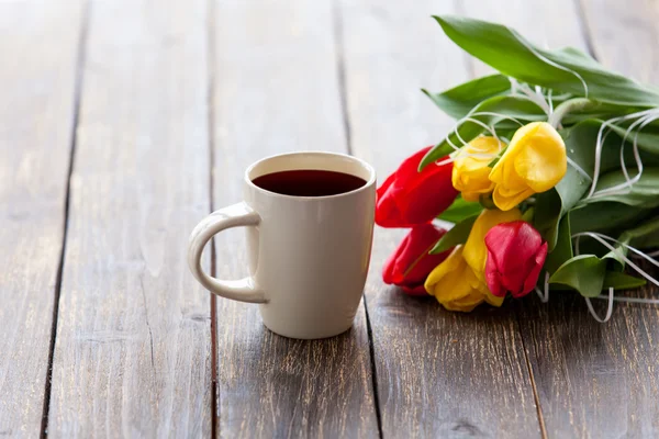 Xícara de café e buquê de tulipas — Fotografia de Stock