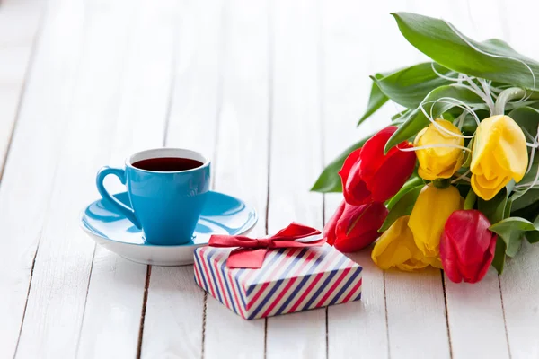 Copo e caixa de presente com buquê de tulipas — Fotografia de Stock