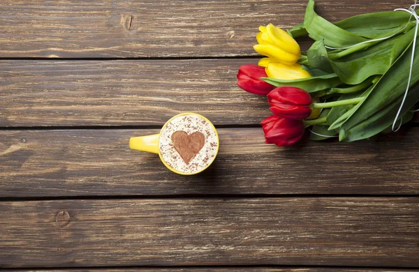 Cappuccino z kształt serca i bukiet tulipanów — Zdjęcie stockowe