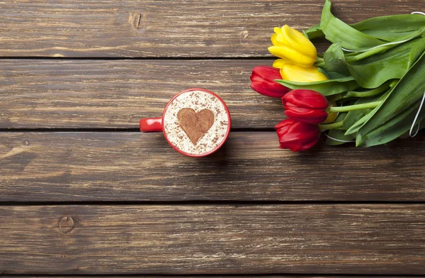 Cappuccino with heart shape and bouquet of tulips — Stock Photo, Image