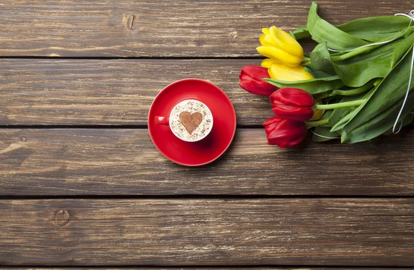 Cappuccino with heart shape and bouquet of tulips — Stock Photo, Image