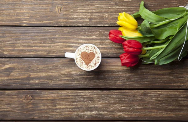Cappuccino com forma de coração e buquê de tulipas — Fotografia de Stock