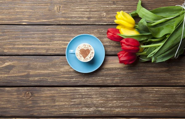 Cappuccino with heart shape and bouquet of tulips — Stock Photo, Image