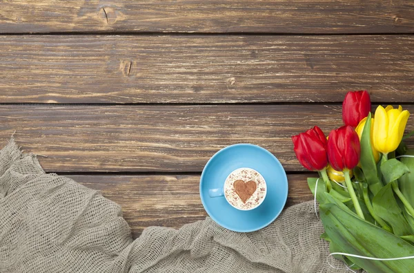 Cappuccino com forma de coração e buquê de tulipas — Fotografia de Stock