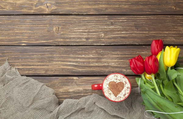 Cappuccino with heart shape and bouquet of tulips — Stock Photo, Image