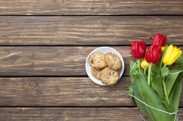 Tulipas e biscoitos em uma mesa de madeira . — Fotografia de Stock