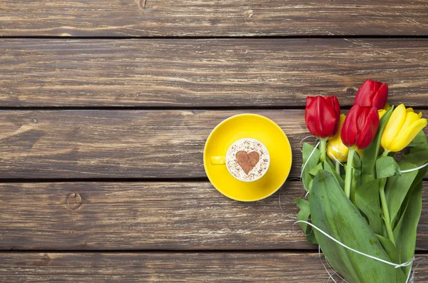 Cappuccino with heart shape and bouquet of tulips — Stock Photo, Image