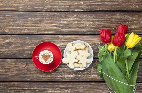 Cup of cappuccino with heart shape and bouquet of tulips with co — Stock Photo, Image