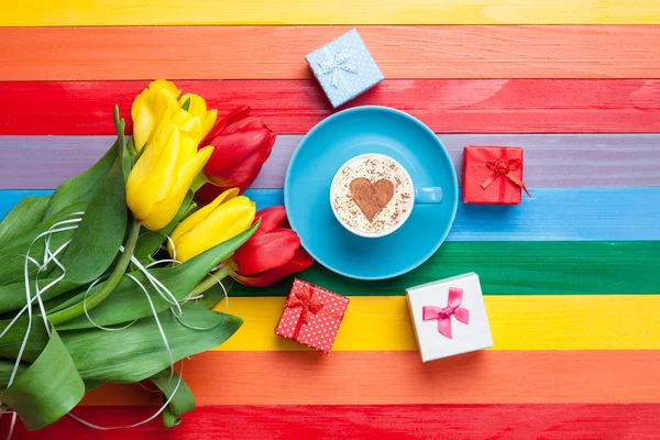 Cup of cappuccino with heart shape and bouquet of tulips — Stock Photo, Image