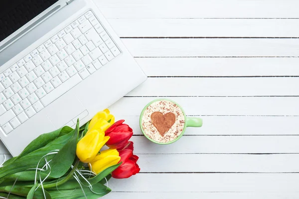 Cup of cappuccino with heart shape and computer — Stock Photo, Image