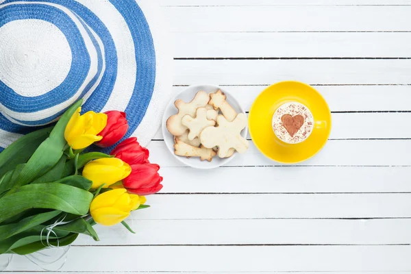 Hat with tulips and cappuccino with cookies — Stock Photo, Image