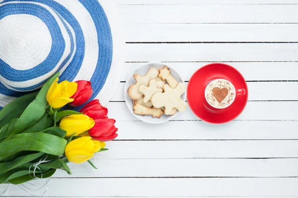 Hat with tulips and cappuccino with cookies — Stock Photo, Image