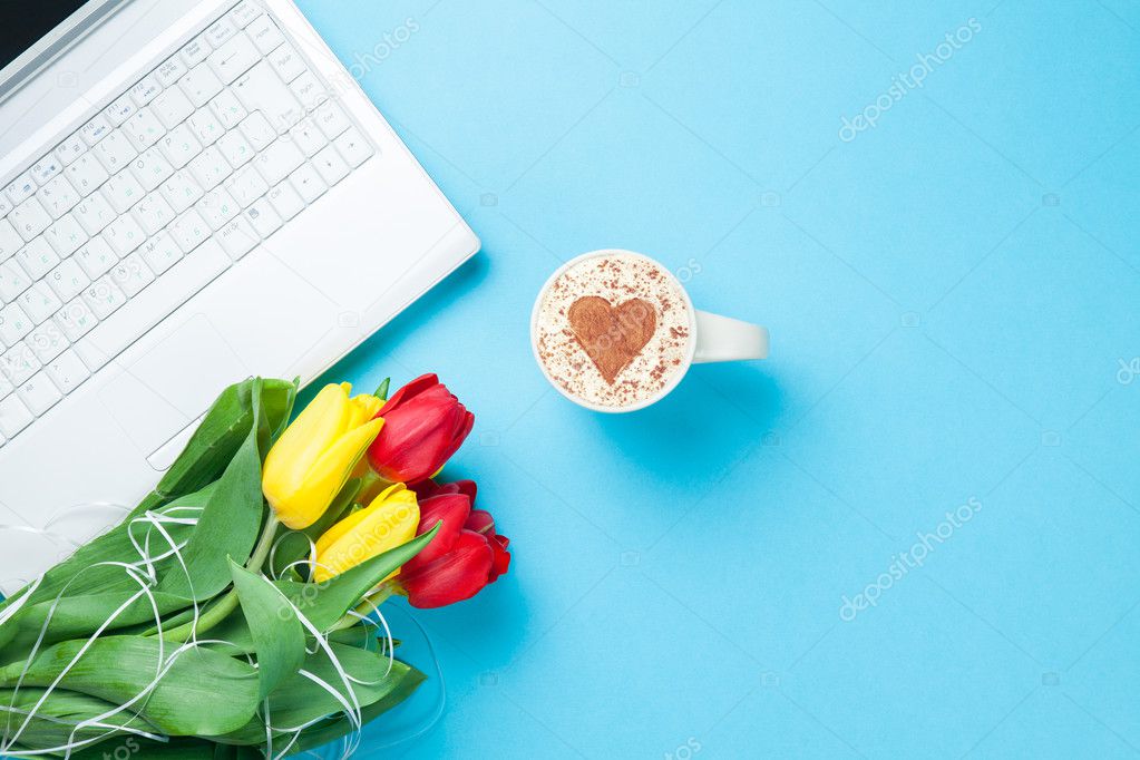 Cup of cappuccino with heart shape and computer