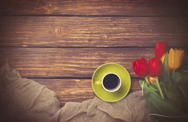 Kopje koffie met tulpen in de buurt van stof — Stockfoto