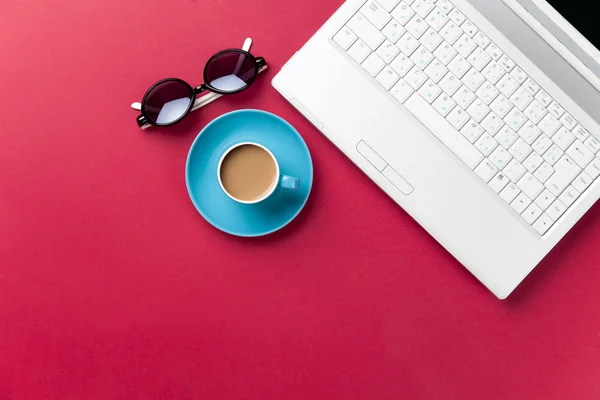 Óculos de sol e xícara de café perto do laptop — Fotografia de Stock