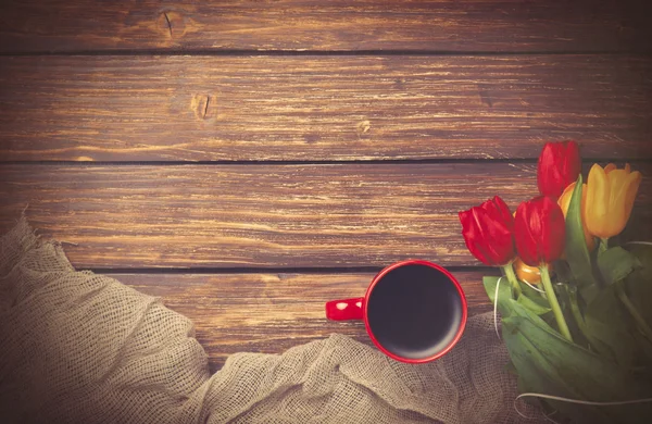 Kopje koffie met tulpen in de buurt van stof — Stockfoto
