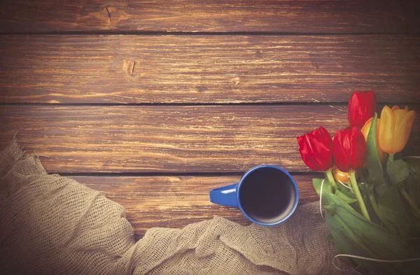 Kopje koffie met tulpen in de buurt van stof — Stockfoto