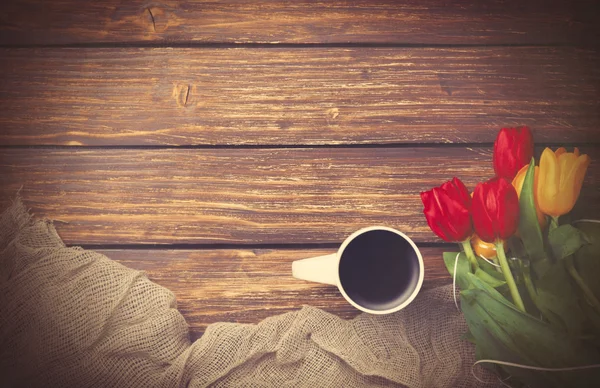 Kopje koffie met tulpen in de buurt van stof — Stockfoto