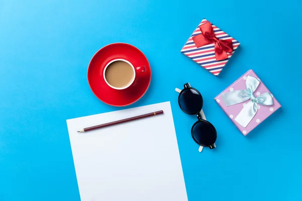 Cup of coffee with sunglasses, gift and paper — Stock Photo, Image