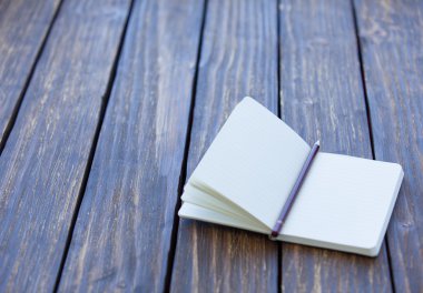 Ahşap masa üstünde defter ve kalem.