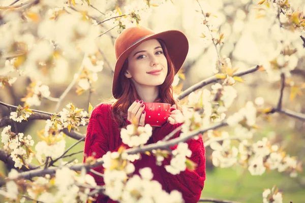 Femme en pull rouge et chapeau avec tasse — Photo