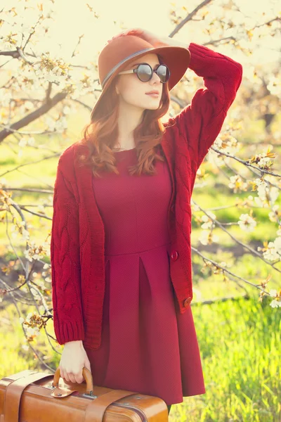 Женщина с чемоданом в цветущем саду яблони — стоковое фото