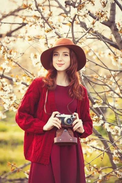 Vrouw in rode trui en muts met camera — Stockfoto