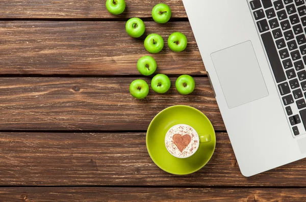 Cappuccino med hjerteform og epler nær laptop – stockfoto