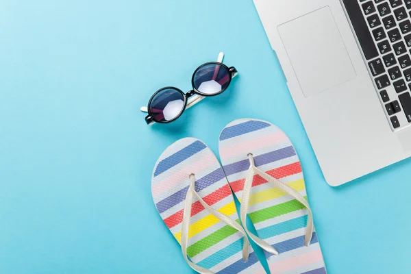 Sunglasses near flip flops and laptop — Stock Photo, Image