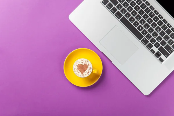 Cup of cappuccino with heart shape and laptop — Stock Photo, Image