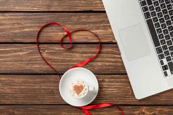 Cappuccino and laptop with red ribbon — Stock Photo, Image