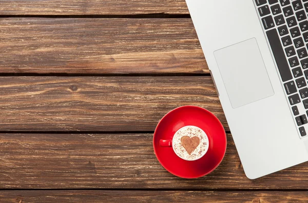 Cup of cappuccino and laptop — Stock Photo, Image