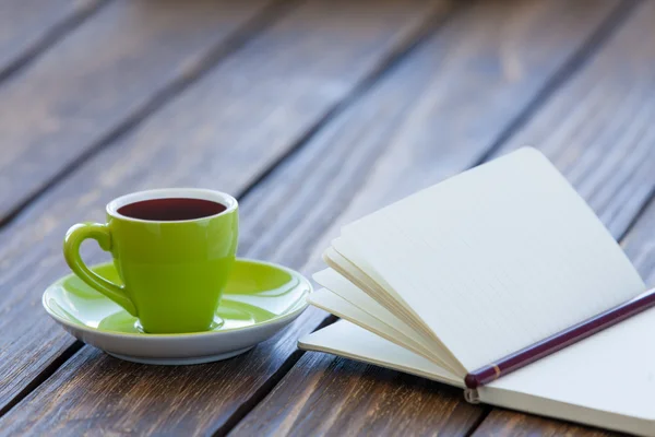Šálek kávy a zápisník s tužkou — Stock fotografie