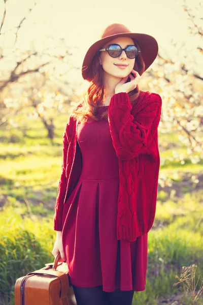 Žena s kufrem v květu apple zahrada — Stock fotografie