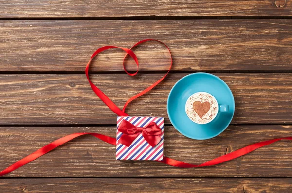 Cup with gift box near ribbon — Stock Photo, Image