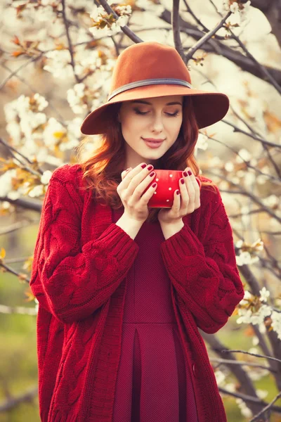 Žena v červený svetr a čepice s pohár — Stock fotografie