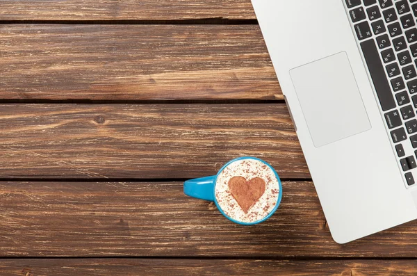 Cup of cappuccino and laptop — Stock Photo, Image